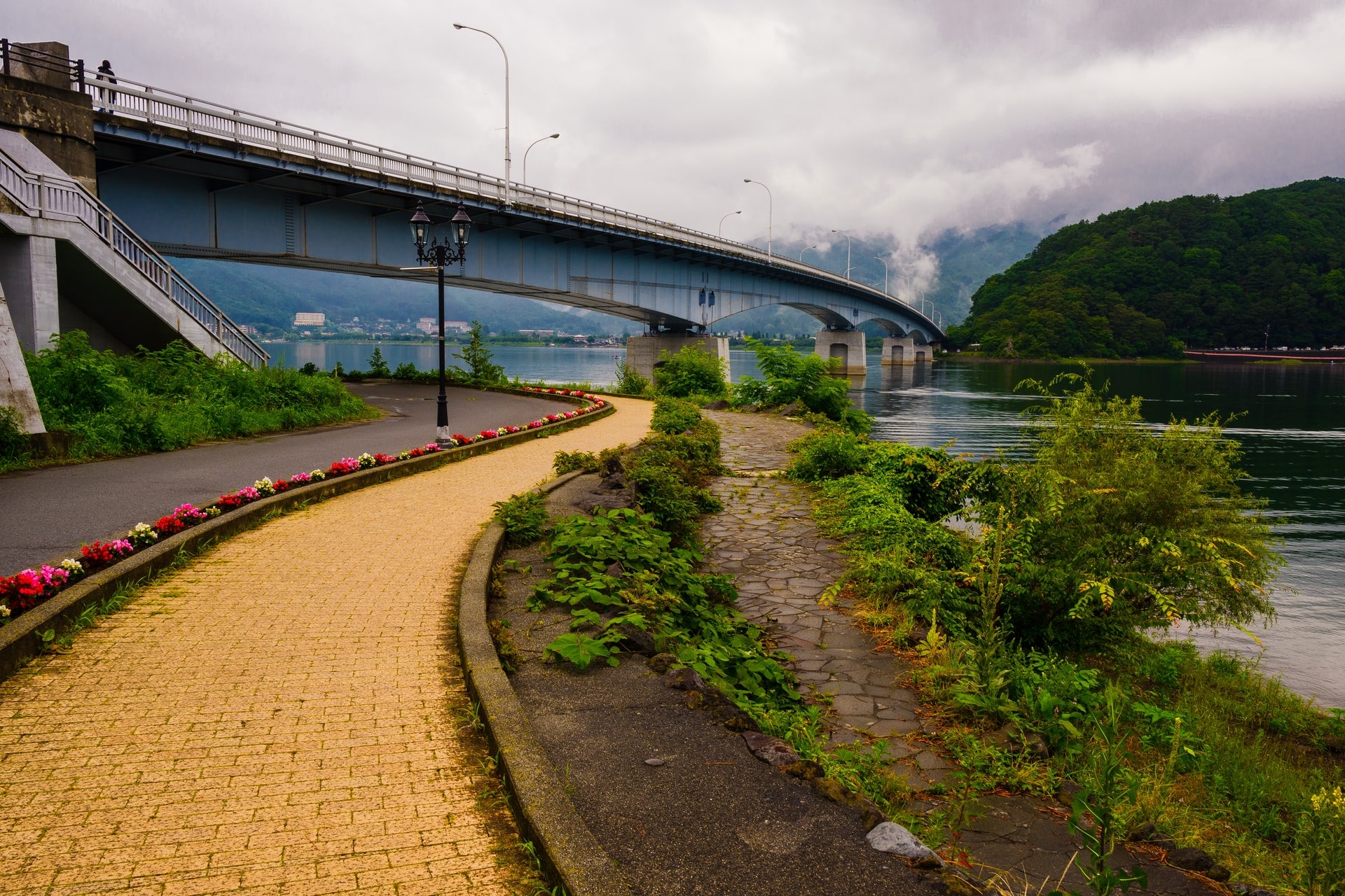 A yellow brick pathway by a river and bridge