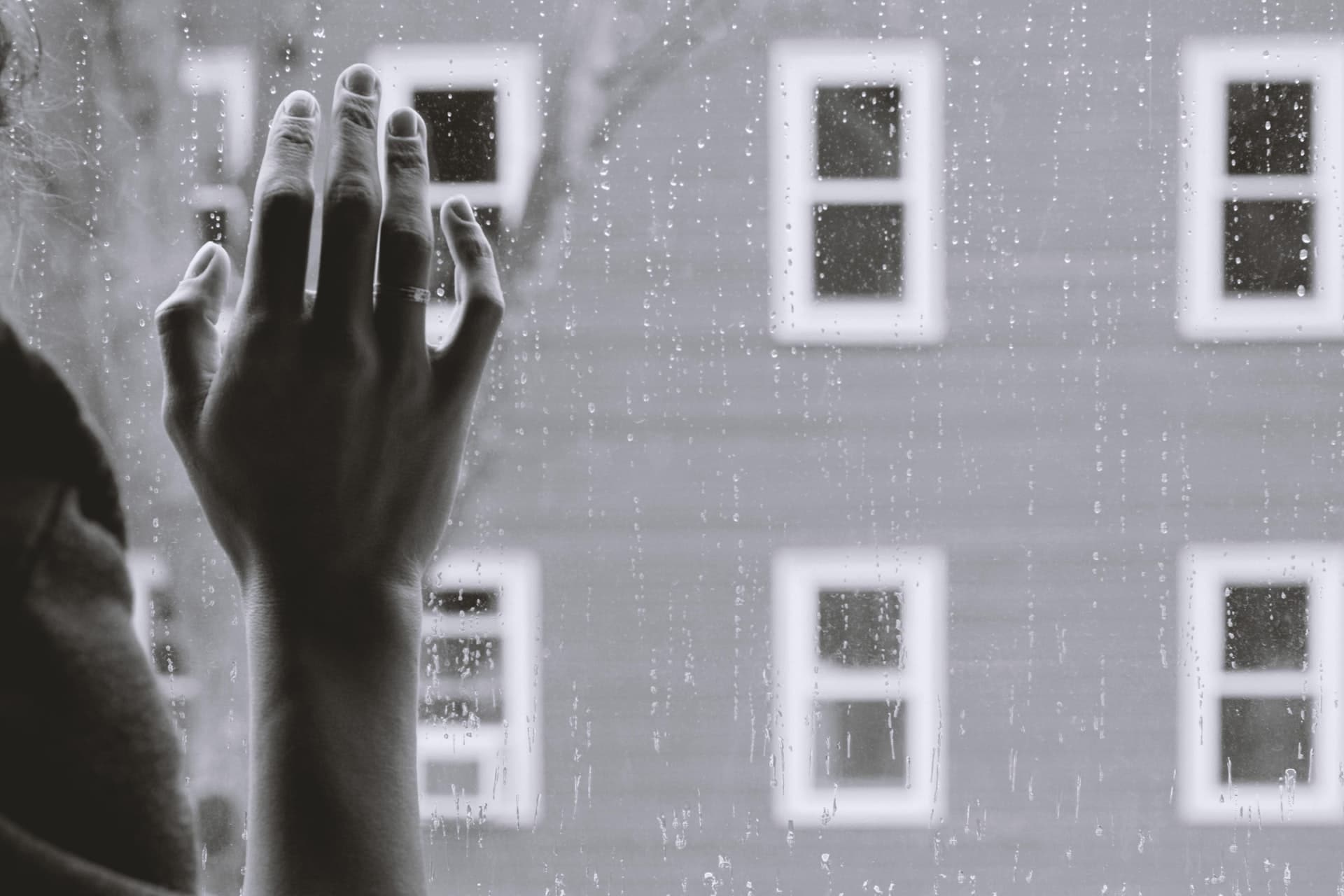 A woman's hand on a rainy window representing the helplessness of trying to enforce a child support award