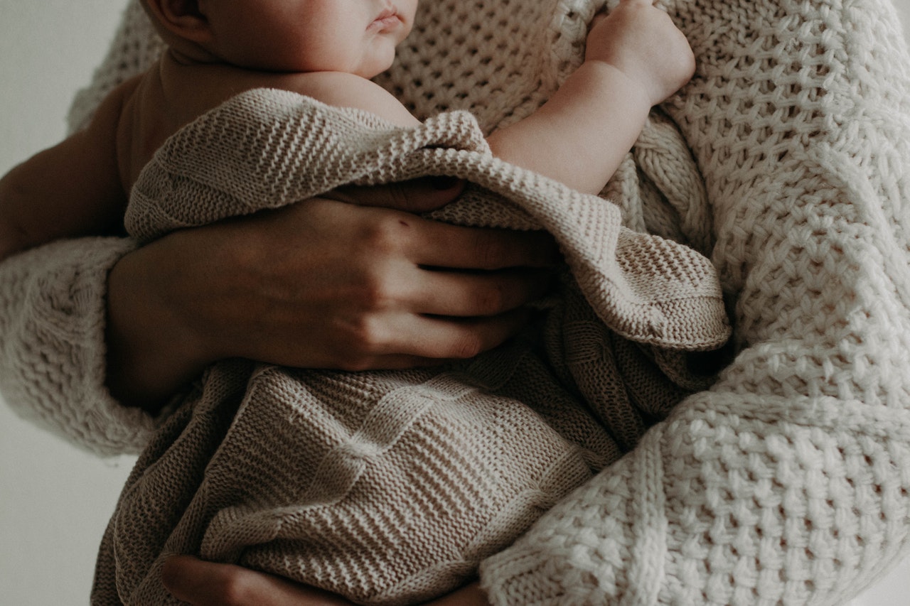 A woman holding a baby, representing questions of parenting when a child is born from sexual assault