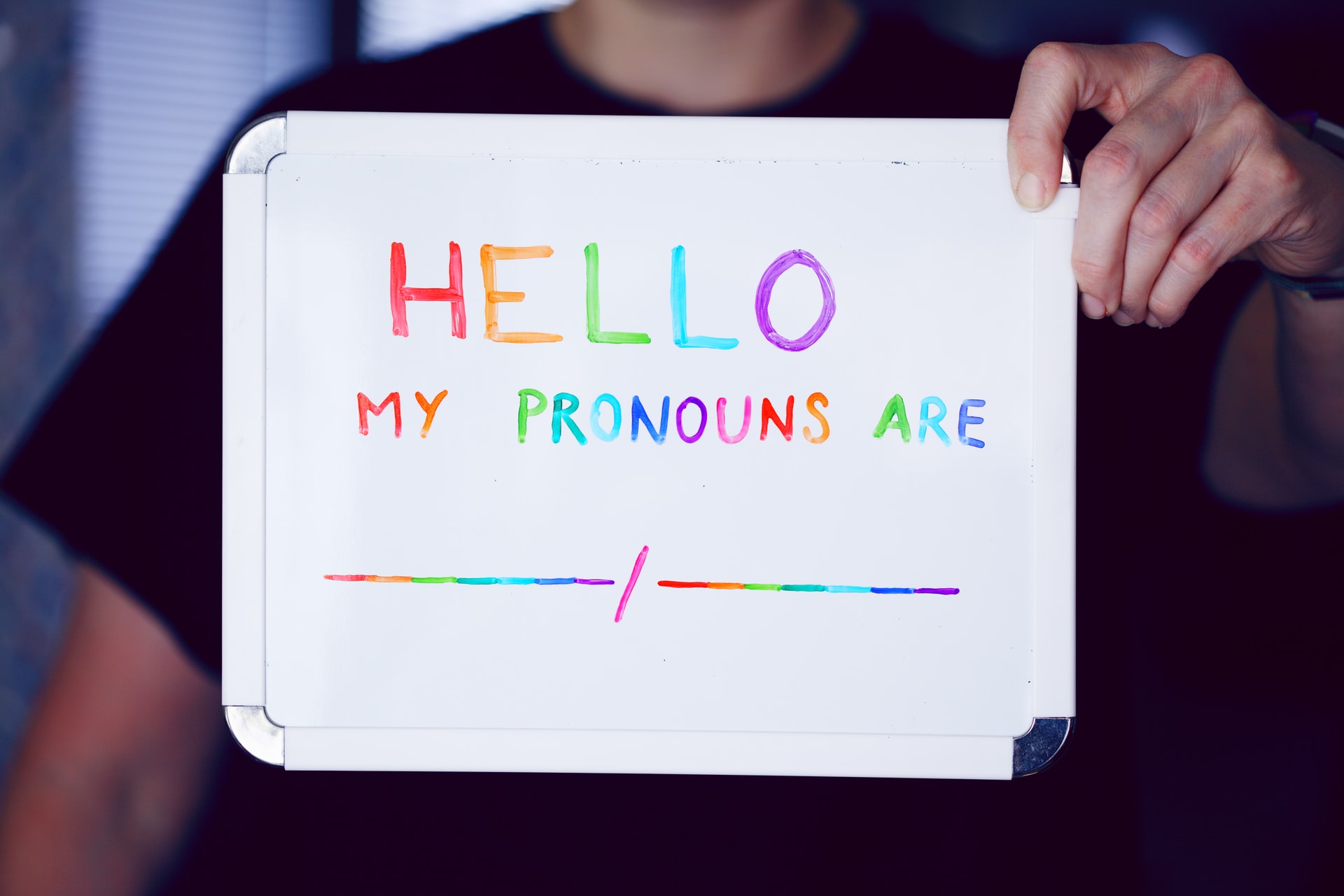 A sign indicating a person's pronouns, representing a father who was arrested for contempt for speaking out publicly against his child's transition