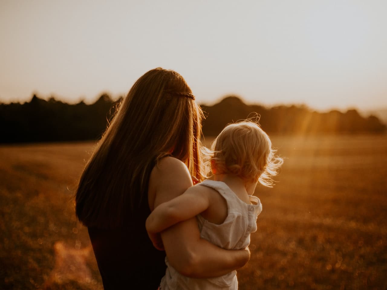 A mother and daughter walking in a field.