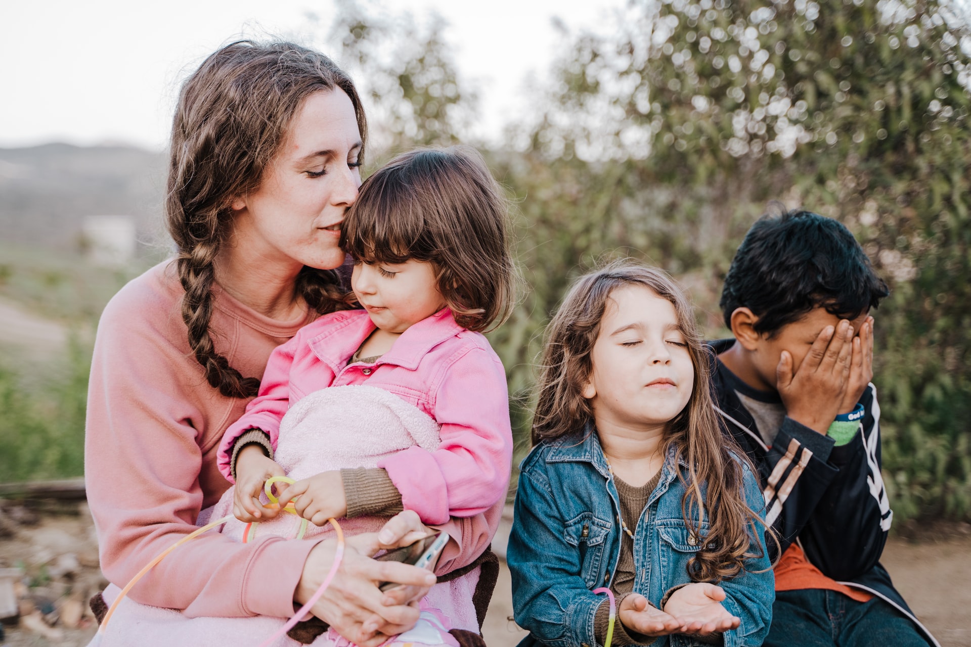 woman in sitting with children outside