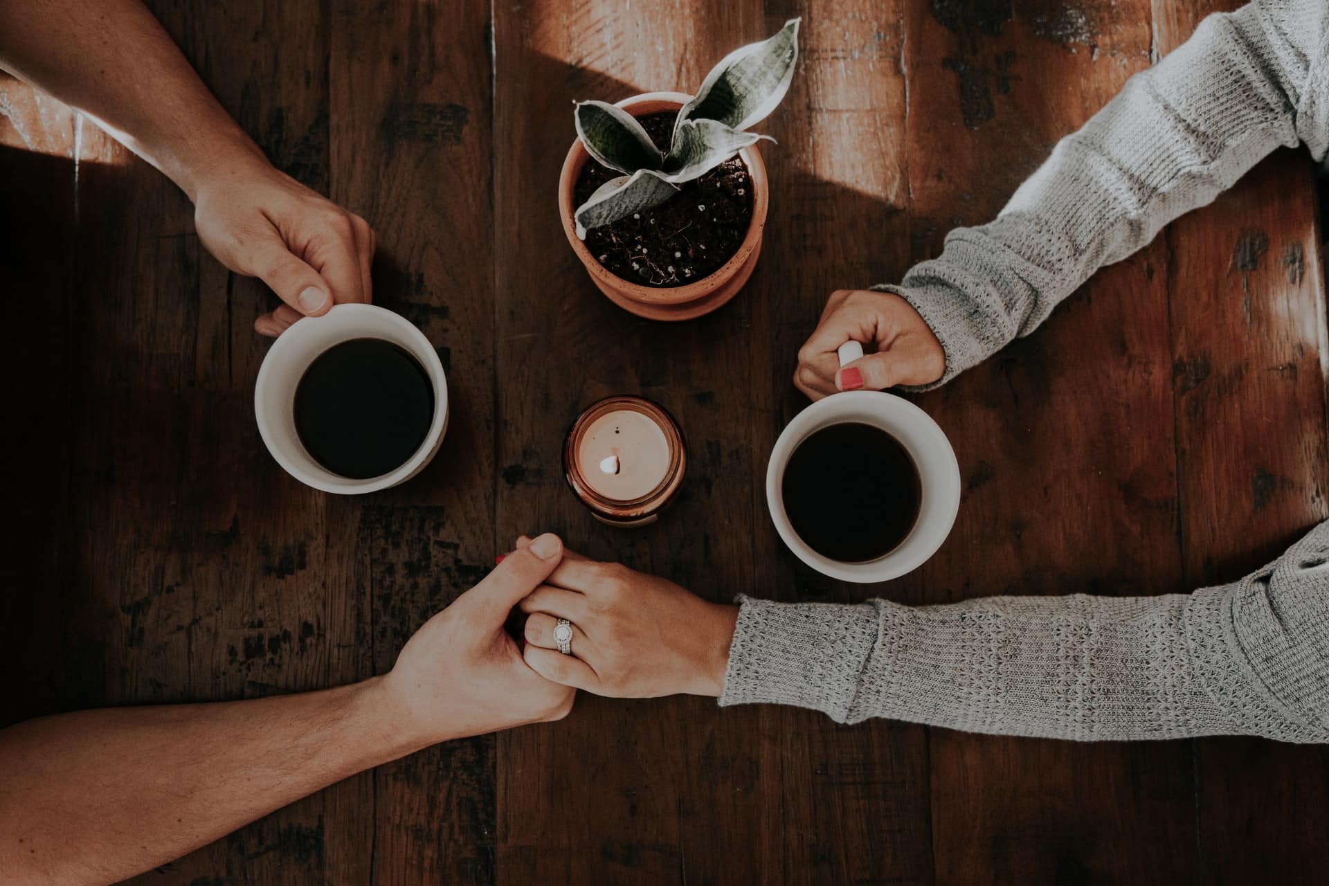 a couple talking and holding hands over coffee