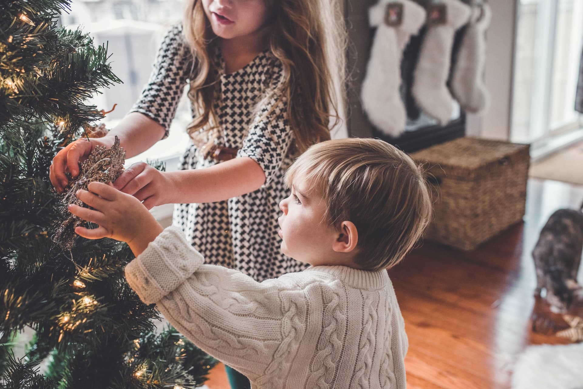 Two children decorating a Christmas tree, representing co-parenting during the holiday season