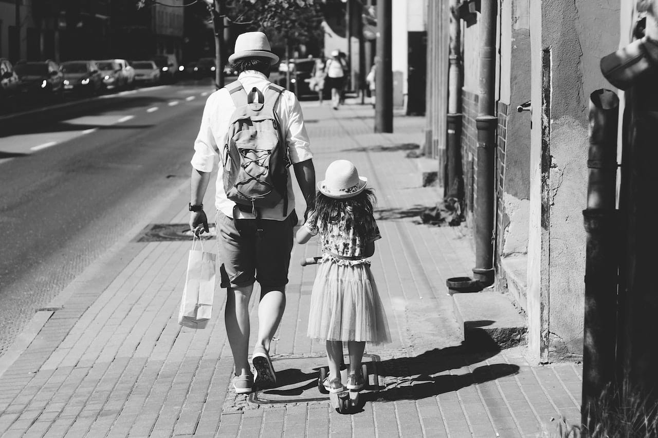 man holding girl's hand while walking on the street