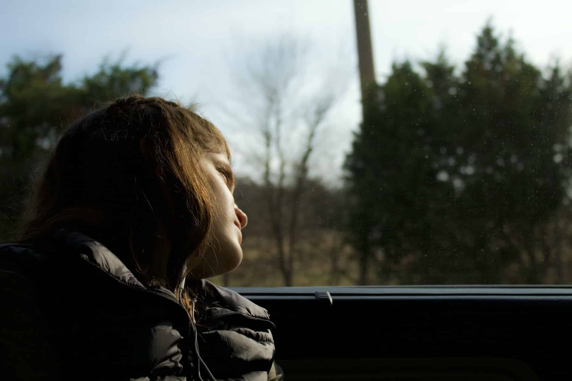 a young girl sitting in car looking out the window