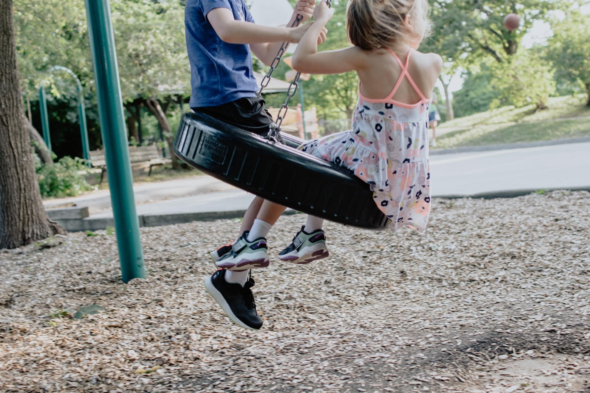 a boy and girl on tire swing in park