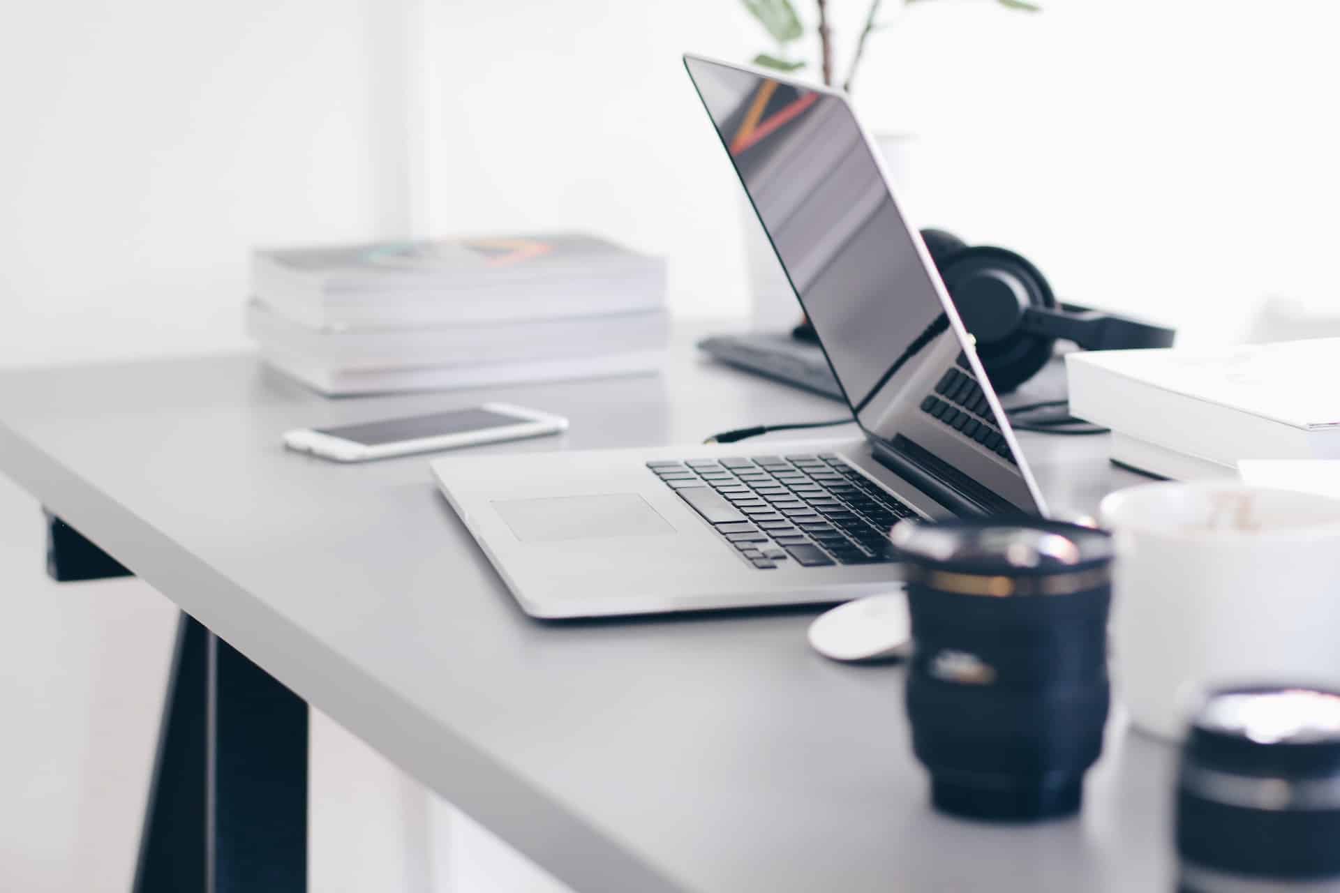 silver macbook pro on white table