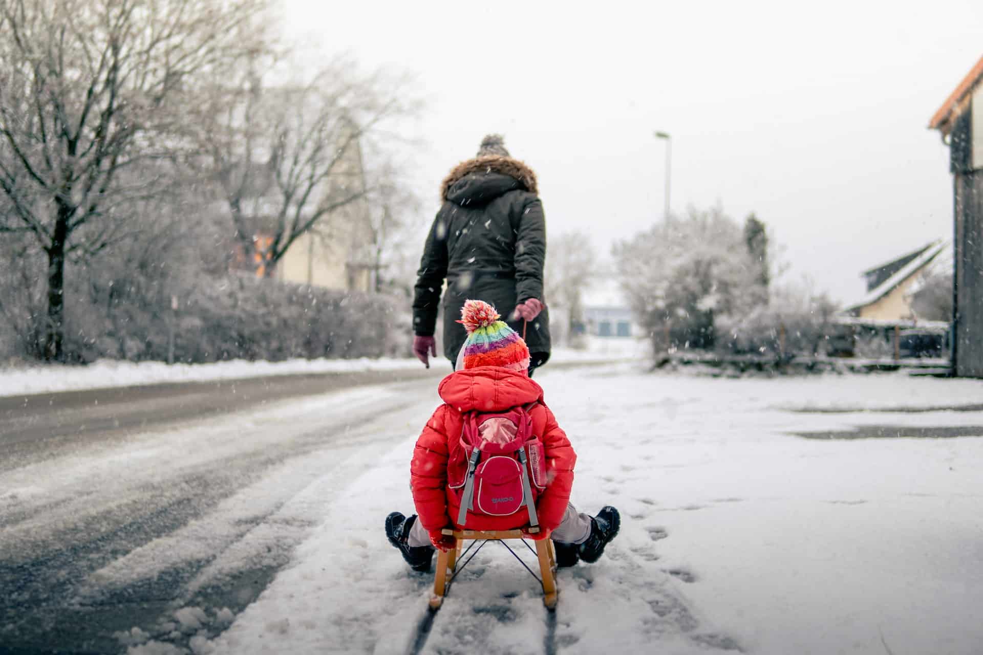 a person pulling a child in sled on sidewalk