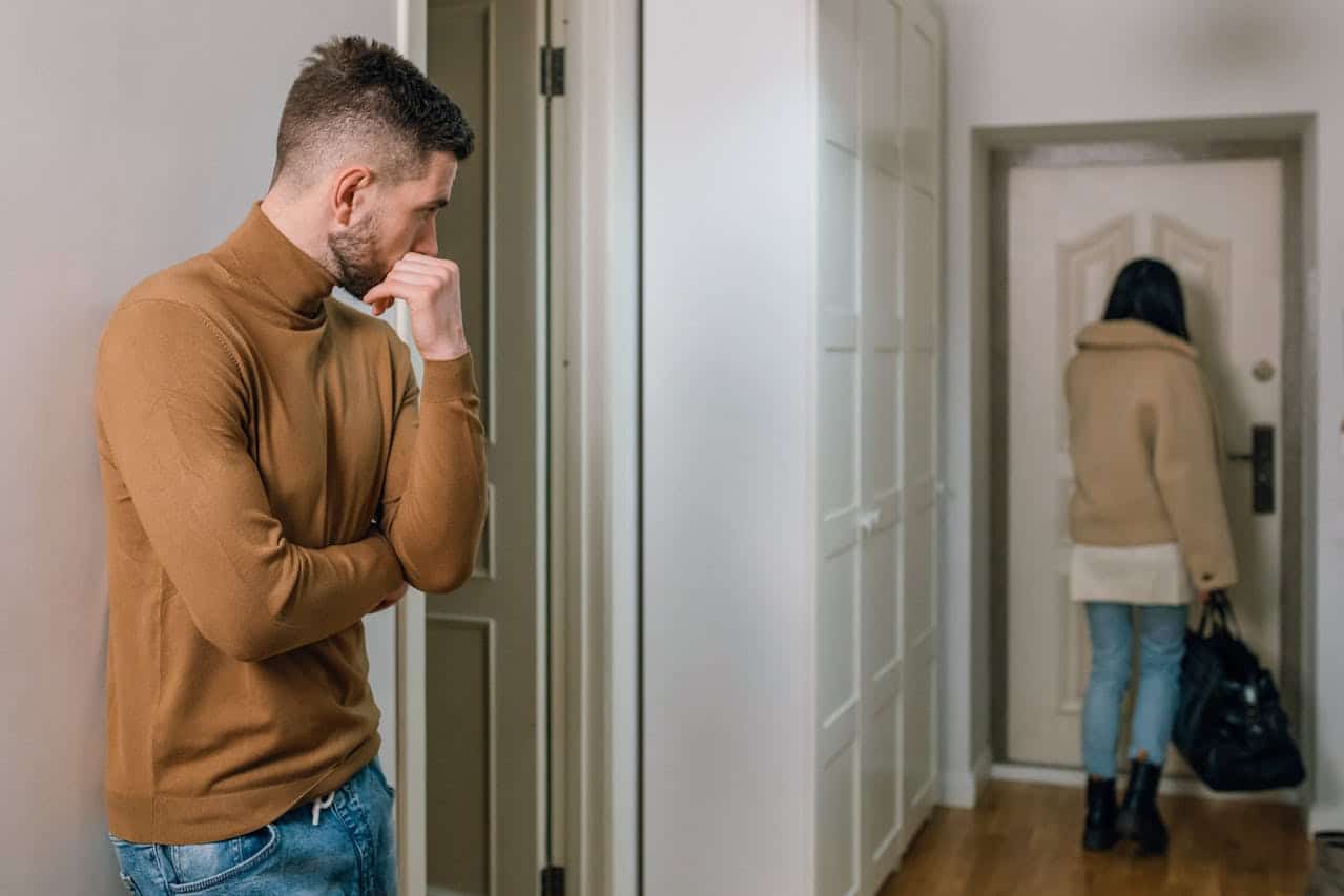 man looking at woman while she walks out the door
