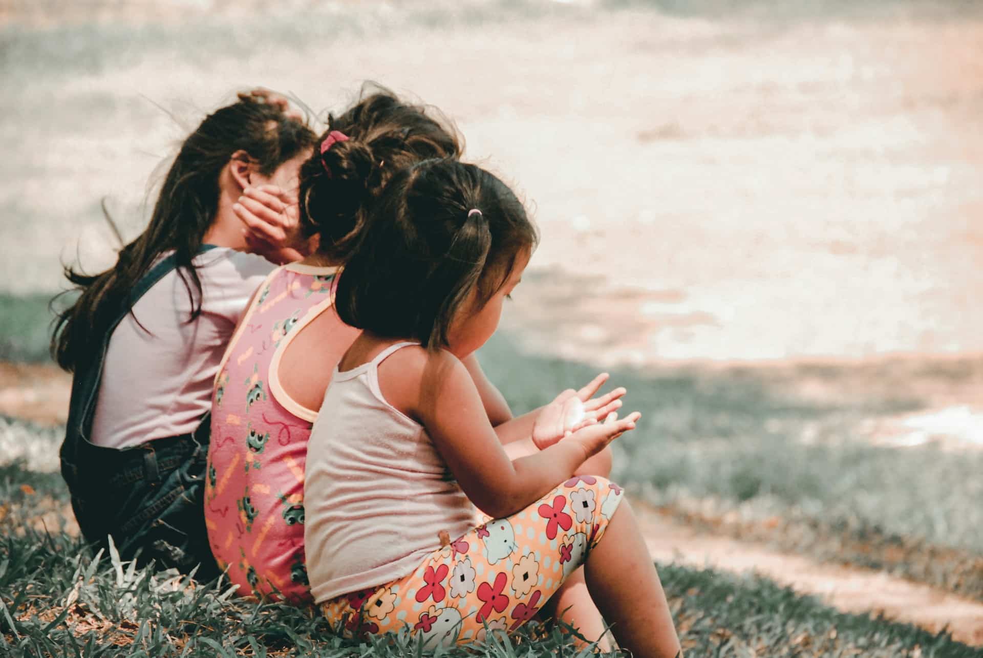 three children sitting in the grass