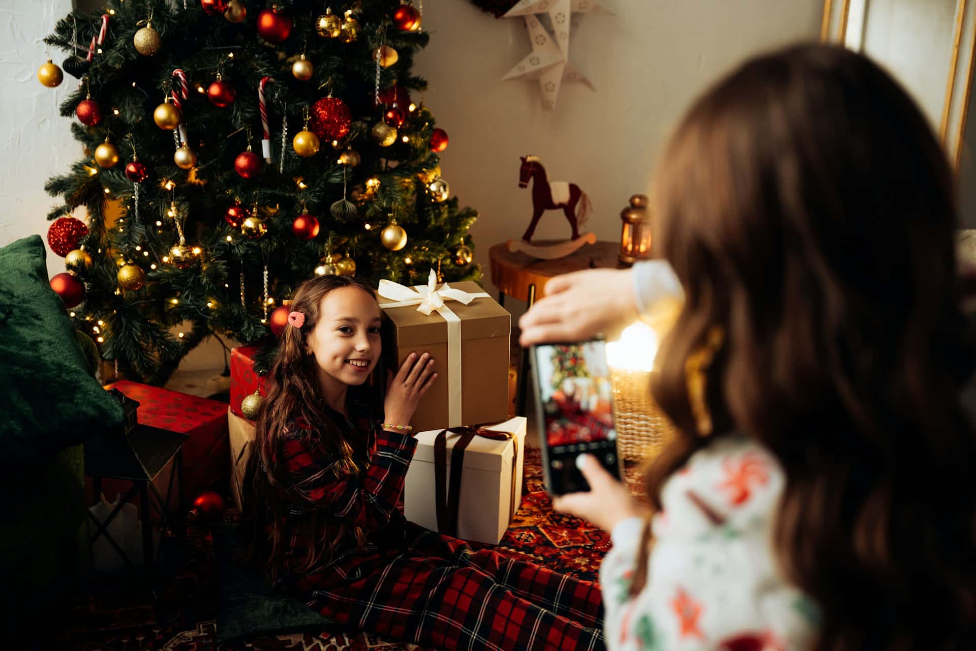 a little girl sitting in front of christmas tree with present